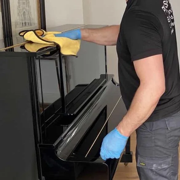 Upright piano prepared for transport, fitted with a protective transit cover