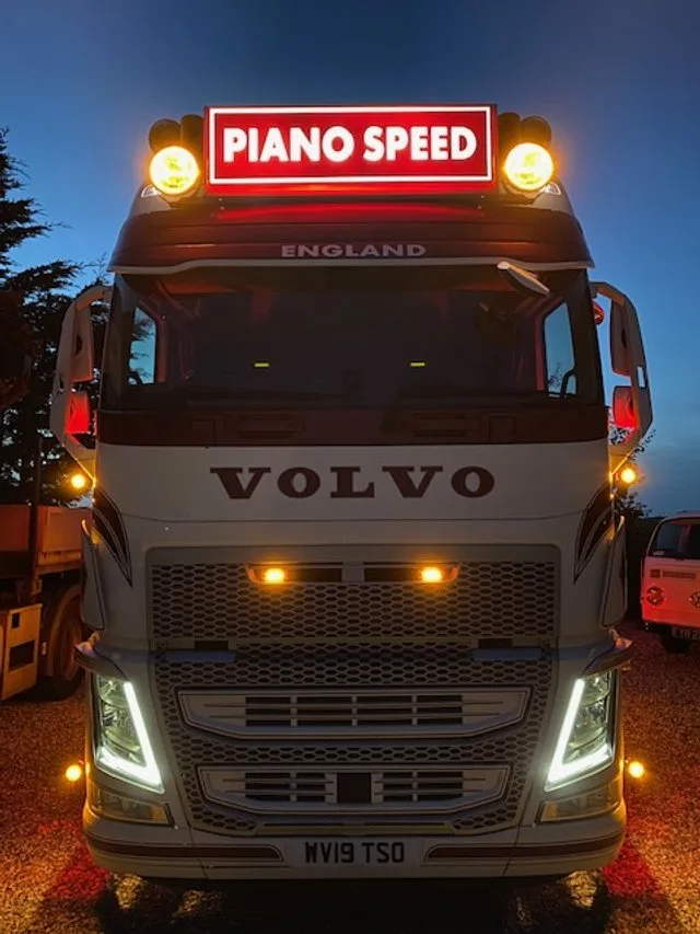 Piano crew carefully loading an upright piano from a house using specialist equipment and transit covers